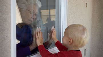 Avó e neto separados por vidro durante a pandemia de Covid-19 - Getty Images