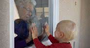 Avó e neto separados por vidro durante a pandemia de Covid-19 - Getty Images
