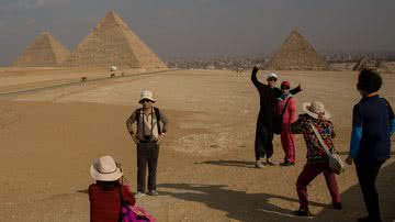 Turistas tirando fotografias na frente das pirâmides de Guizé em 2016 - Getty Images