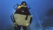 Arqueólogo mergulhador segurando grande placa de cobre encontrada em naufrágio - Divulgação/Texas A&M University/Cemal Pulak