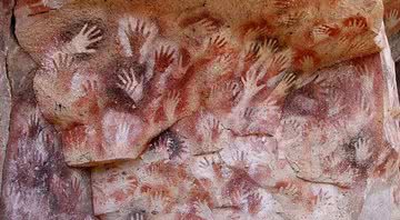 Pintura rupestre de mãos na famosa "Caverna de Las Manos" - Domínio Público