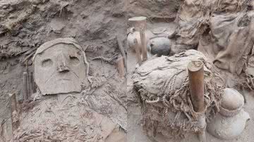 Restos mortais de um indivíduo com máscara e objetos desenterrados - Divulgação/Programa de Arqueologia da PUCP "Vale de Pachacámac"