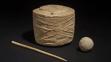 'Tambor de giz', uma das mais intrigantes e importantes descobertas arqueológicas do século, junto a uma bola de giz e uma agulha de osso polido - Foto por Chris Trebble pelo Wikimedia Commons