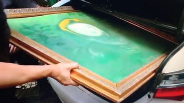 Momento de vídeo em que mostra agente da polícia forçando obra de arte no porta-malas do carro - Reprodução/Video/Twitter @disangermano