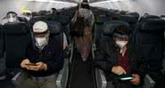 Pessoas aguardam decolagem de avião com máscaras - Getty Images