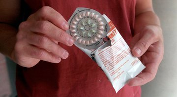 Imagem ilustrativa de mulher segurando cartela de anticoncepcionais - Getty Images