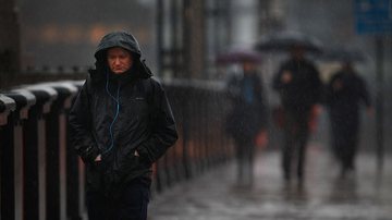 Homem andando na chuva com semblante triste - Crédito/Getty Images