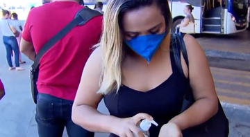 Mulher com máscara passa álcool em gel em terminal de ônibus no Brasil - Divulgação/ Youtube