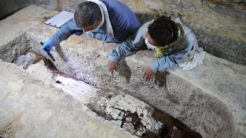O egiptólogo Ramadan Hussein (à esquerda) e a especialista em múmias Salima Ikram examinam um sarcófago de calcário em Sacará - Ministério do Turismo e Antiguidades do Egito