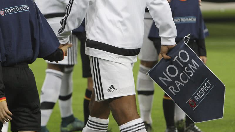 O jogador Juan Cuadrado segurando um flamula de campanha antirracista da FIFA