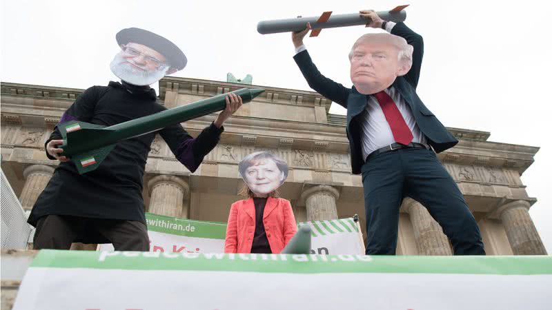 Atores vestidos como líderes religiosos Ali Chamenei, Angela Merkel e Donald Trump realizam uma ação de teatro de rua como parte de uma manifestação anti-guerra - Getty Images