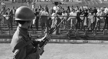 Um soldado do Exército chileno vigia prisioneiros políticos mantidos no Estádio Nacional de Santiago - Getty Images