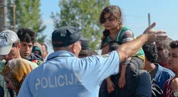 Policial ordenando grupo de imigrantes - Getty Images