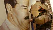 Militar estadunidense removendo cartaz com rosto de Saddam Hussein, durante a Guerra do Iraque - Getty Images