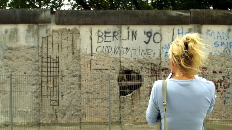 Imagem de uma mulher olhando para o Muro de Berlim, em 2001 - Getty Images