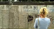 Imagem de uma mulher olhando para o Muro de Berlim, em 2001 - Getty Images