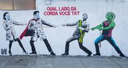 Grafite representando Jair Bolsonaro e o coronavírus em um cabo de guerra contra os trabalhadores da saúde - Getty Images