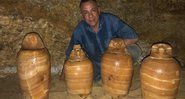 Arqueólogo ao lado de objetos encontrados em Tuna al-Gabal - Divulgação - Ministério do Turismo e Antiguidades
