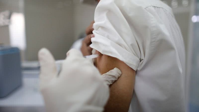 Profissional de saúde aplica vacina em paciente