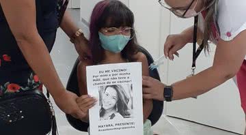 Menina segura cartaz com foto da mãe no momento da vacinação - Divulgação / TV Globo