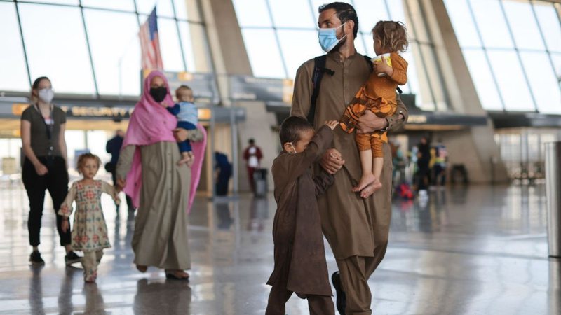 Família afegã caminha em aeroporto
