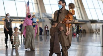 Família afegã caminha em aeroporto - Getty Images