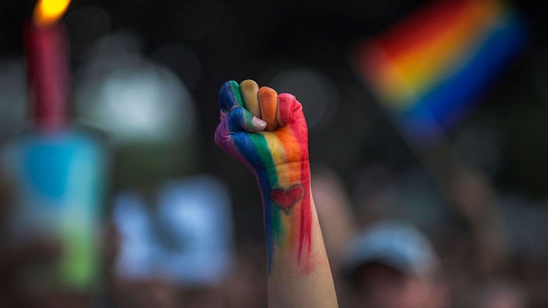 Mão pintada com as cores do orgulho LGBT+