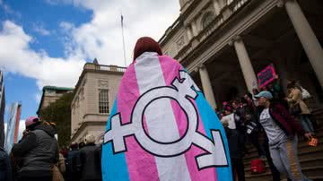 Pessoa utiliza bandeira da comunidade trans durante protesto - Getty Images