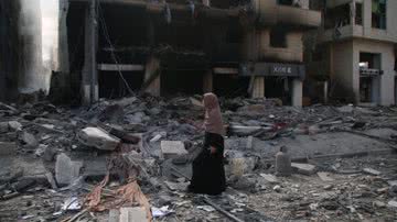 Moradora da Faixa de Gaza andando sob escombros - Getty Images
