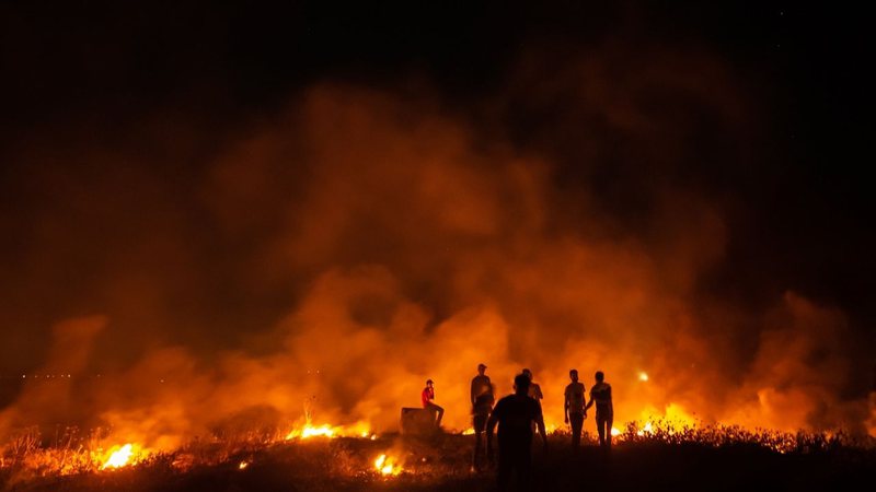 Palestinos queimam pneus durante uma manifestação a leste da Cidade de Gaza, na fronteira com Israel, em 15 de junho de 2021 - Getty Images