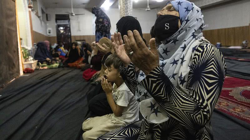 Mulheres e crianças afegãs rezam em uma mesquita