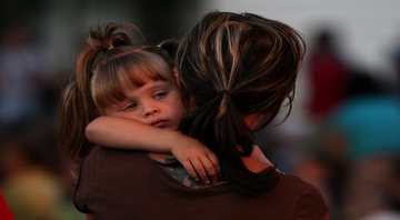 Mulher segurando no colo sua filha - Getty Images