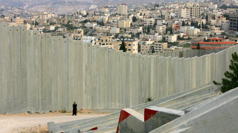 Uma mulher palestina caminha ao longo do muro em 26 de março de 2006 - Getty Images
