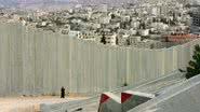Uma mulher palestina caminha ao longo do muro em 26 de março de 2006 - Getty Images