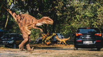 Foto dos dinossauros robóticos caminhando entre os carros - Divulgação