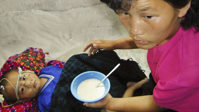 Mãe norte-coreana alimenta filho com o auxílio do Programa Alimentar Mundial, em 2004 - Getty Images