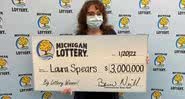Laura segurando cheque ilustrativo com prêmio - Divulgação / Michigan Lottery