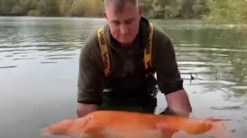 Andy Hackett segurando o peixe dourado de 30 quilos - Divulgação / Youtube / The Guardian