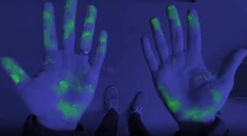 Mãos com o pó de brilho vistas em luz negra - Divulgação/Youtube
