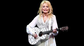 Dolly Parton com violão durante apresentação em 2014 - Getty Images