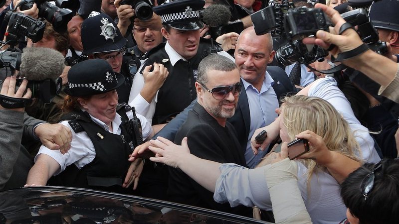 George Michael sai escoltado por policiais durante assédio midiático - Getty Images