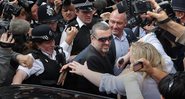 George Michael sai escoltado por policiais durante assédio midiático - Getty Images