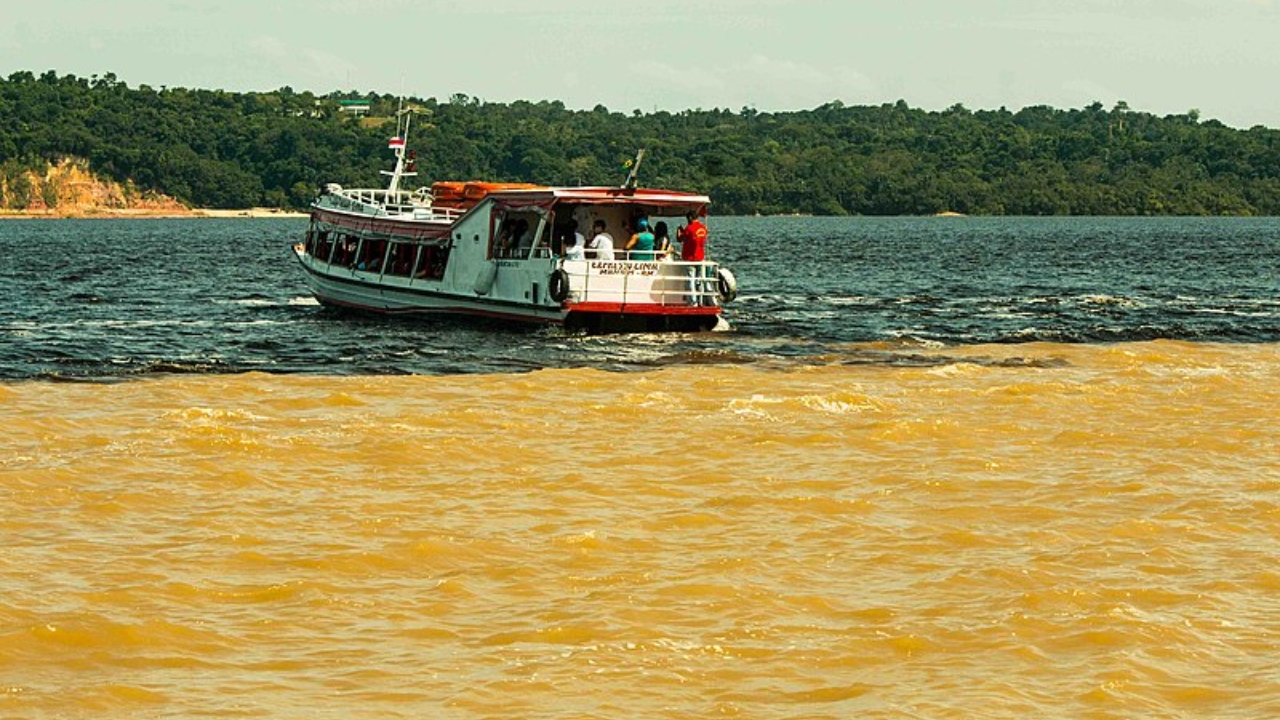 Fotografia de barco navegando próximo ao encontro das águas dos rios Tapajós e Amazonas