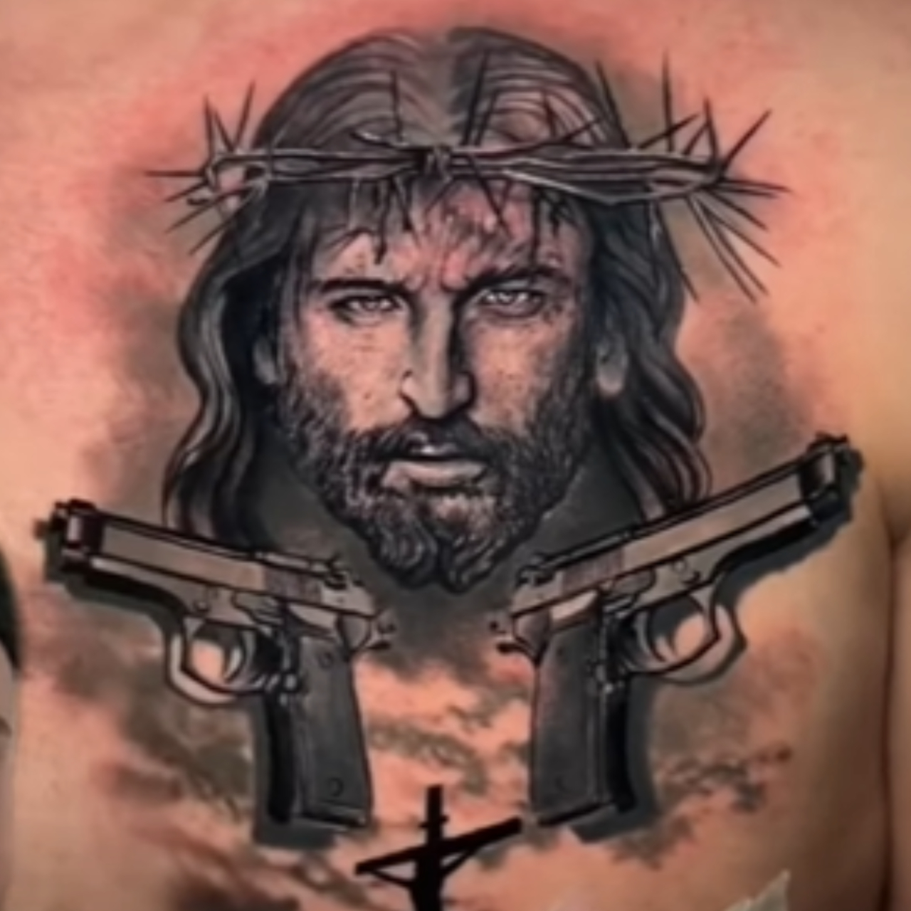 Tatuagem com imagem de Jesus Cristo e duas armas