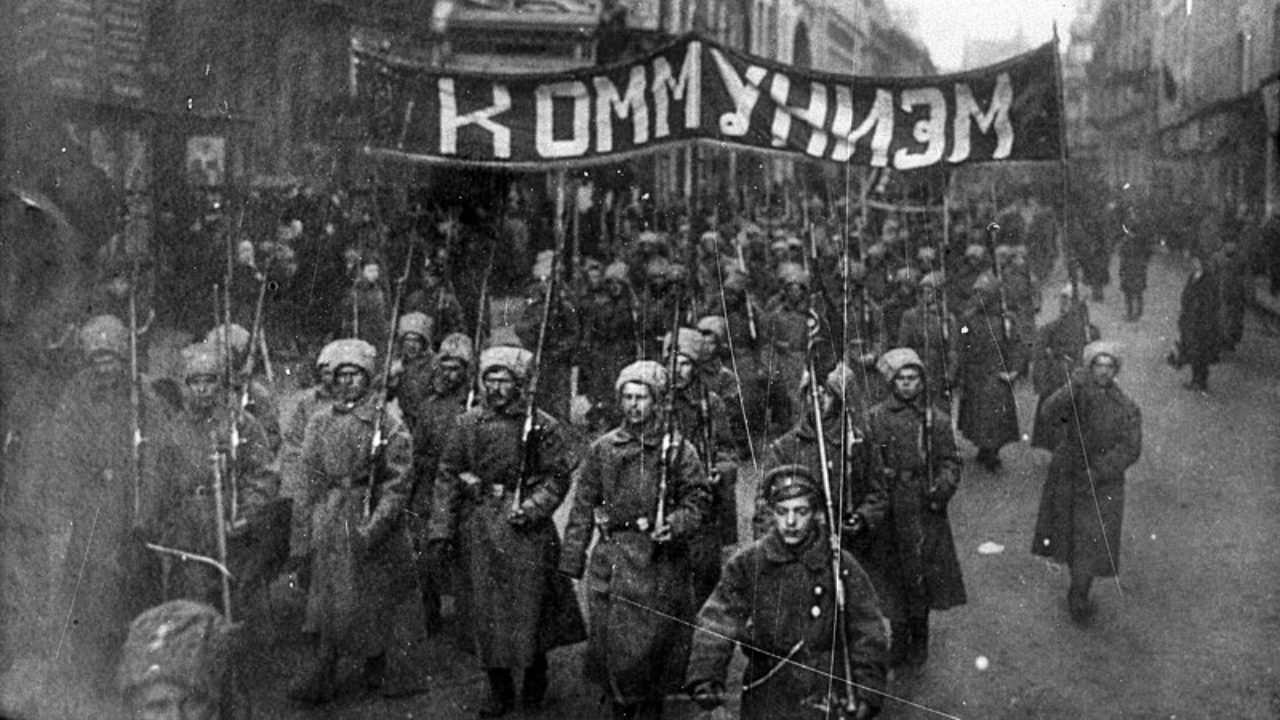 Emblemática fotografia tirada durante a Revolução Russa, com soldados segurando uma bandeira escrita 'comunismo'