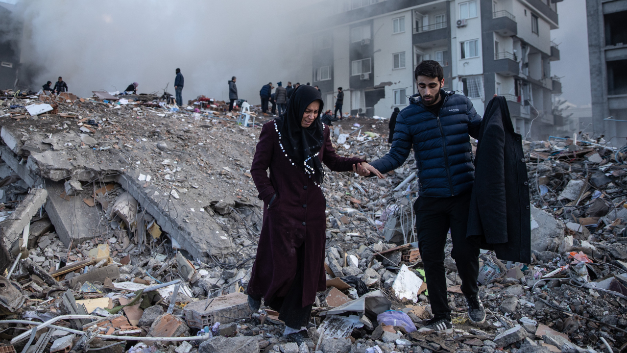 Pessoas andando sobre escombros resultantes do terremoto