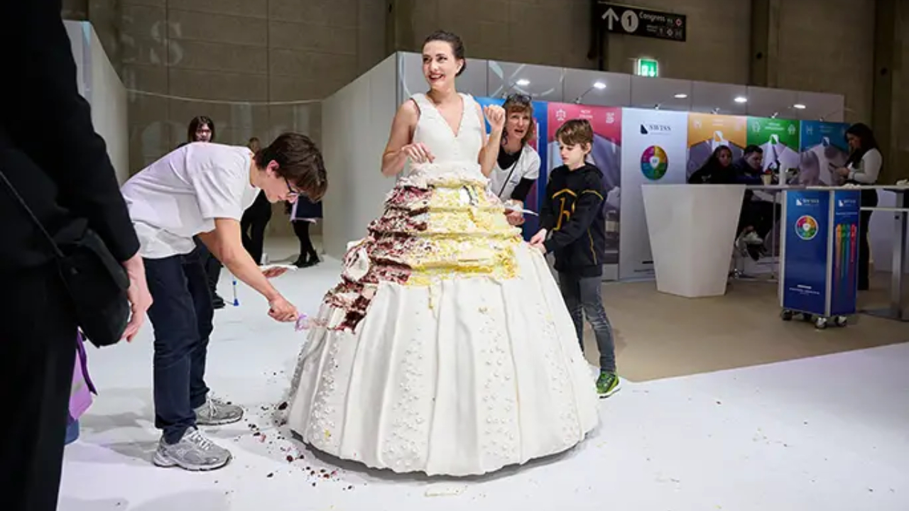 Modelo utilizando vestido de casamento feito de bolo, já servindo aos convidados do evento